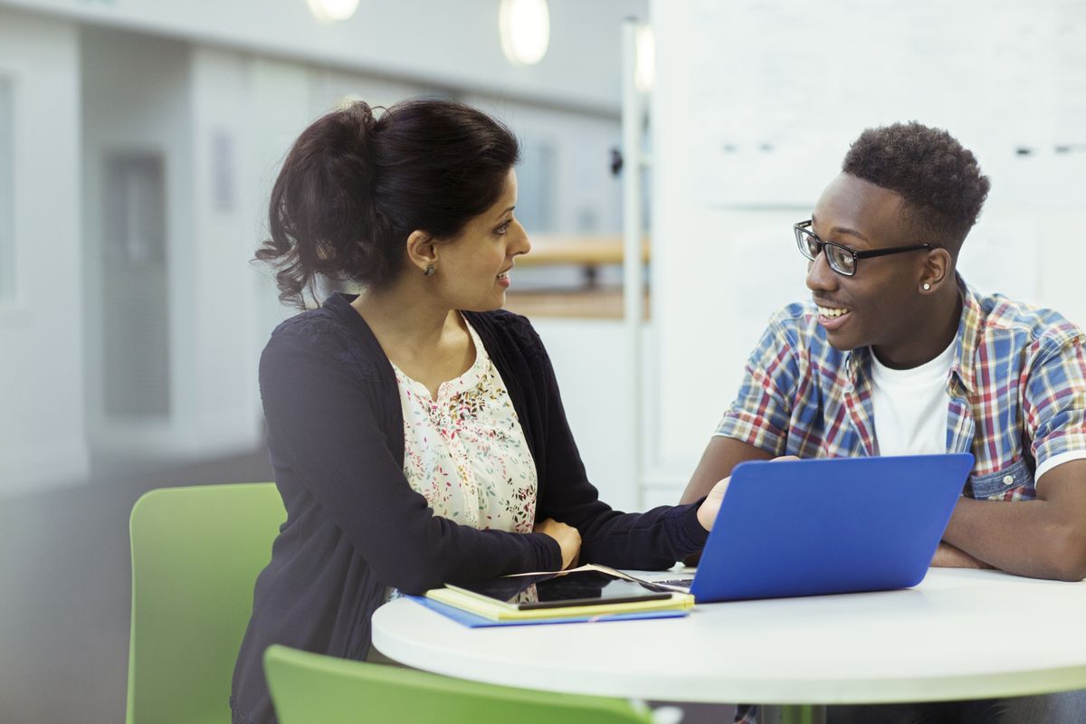 A mentor guiding a student using a laptop